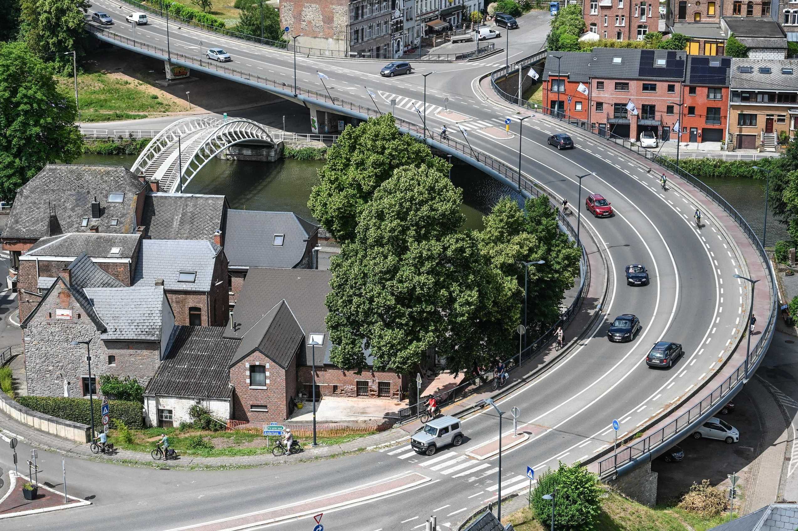 Aerial view of a curved road over a river in Belgium with cars and cyclists driving.