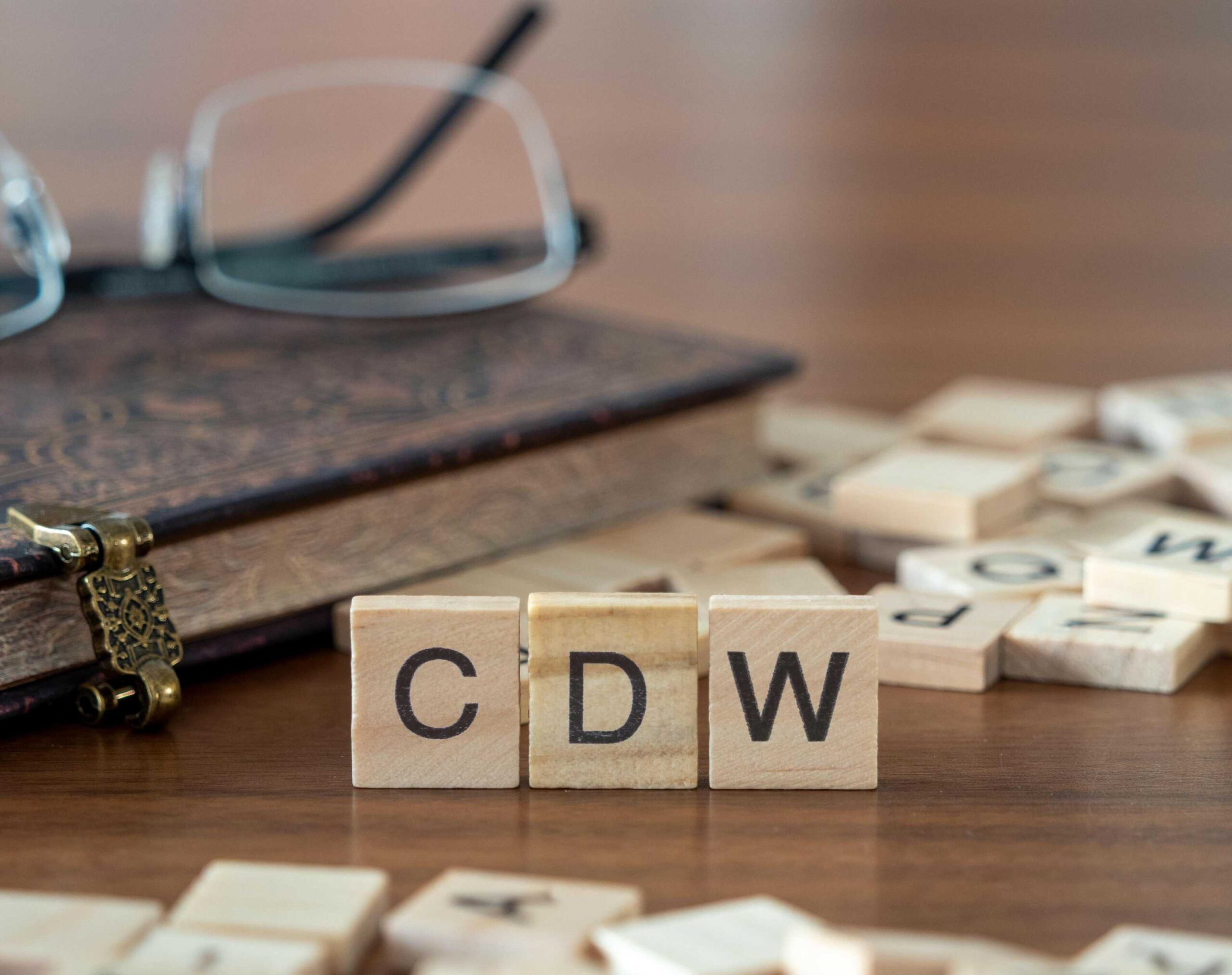 Acronym for Collision Damage Waiver 'CDW' written out in wooden letter tiles sitting on a table.